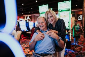 An older couple playing a slot machine with smiles on their faces