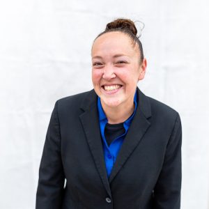 Smiling woman with hair in bun wearing a suit jacket with blue undershirt