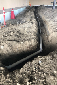 Underground plumbing piping for back of house being buried in trench