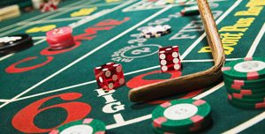 Craps table with dealer scooping dice with the table rake