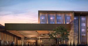 Modern multi-story office building at dusk with a glass façade and a covered entrance, pedestrians near the lobby.
