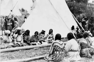 Native American women sitting in a circle playing a traditional stick game with sticks and bones during a cultural gathering