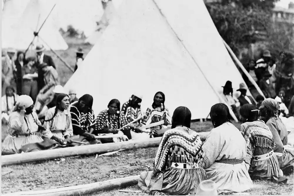 Native American women sitting in a circle playing a traditional stick game with sticks and bones during a cultural gathering
