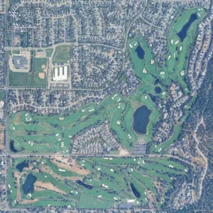Aerial view of a golf course with surrounding suburban streets and ponds