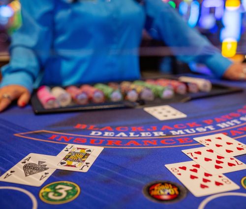 Dealer standing at blackjack table with a blackjack laid out in front
