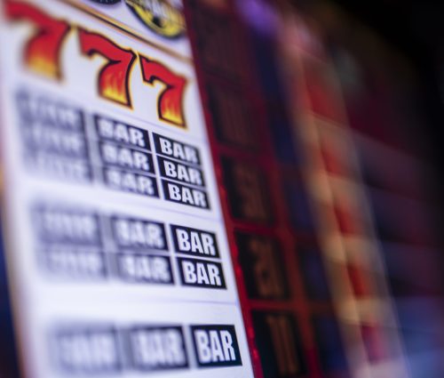 A partially blurred image of a winning slot machine with 777 and Bar Bar Bar visible